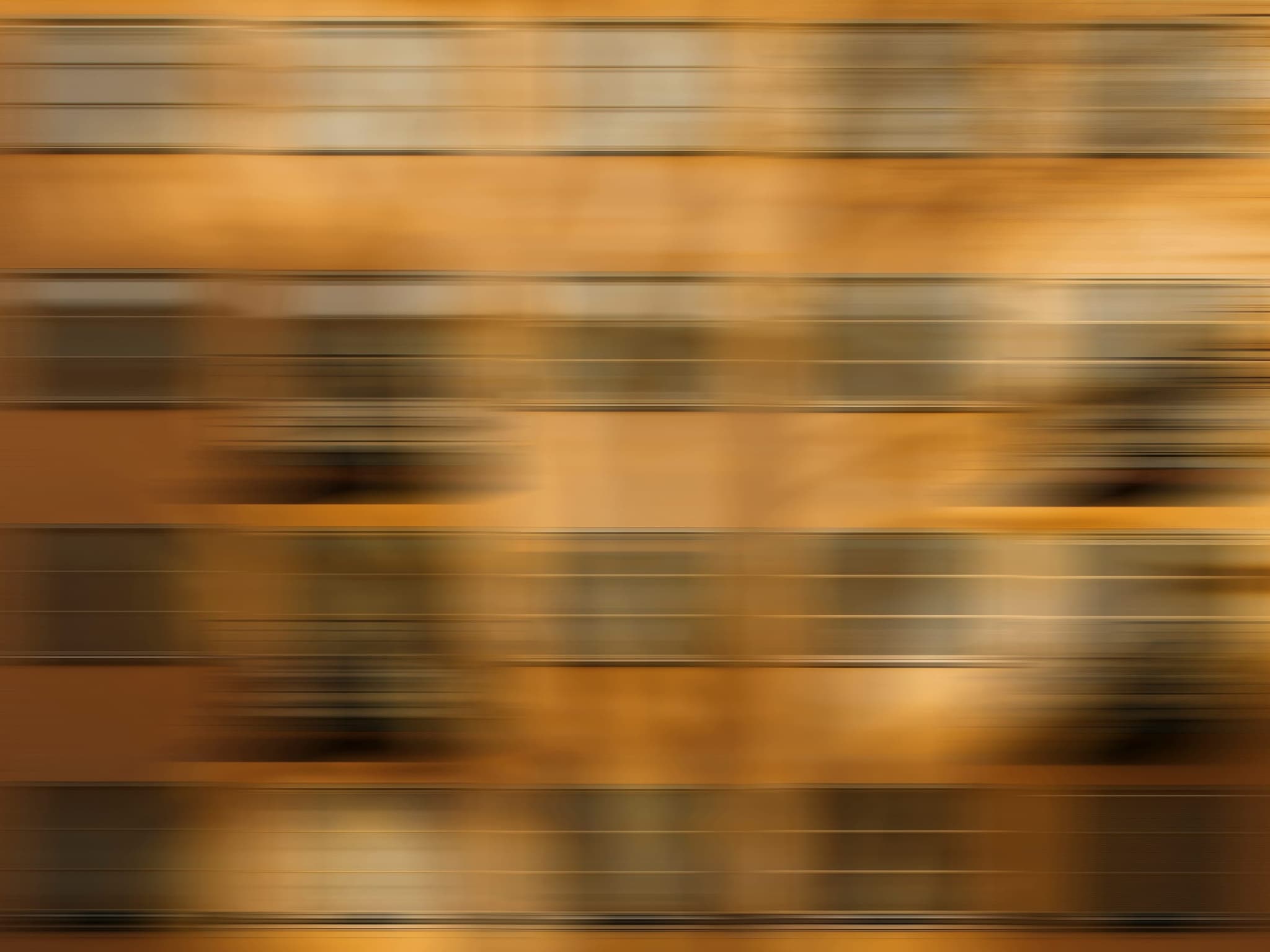 Warm-toned building facade with rows of windows, blurred by motion