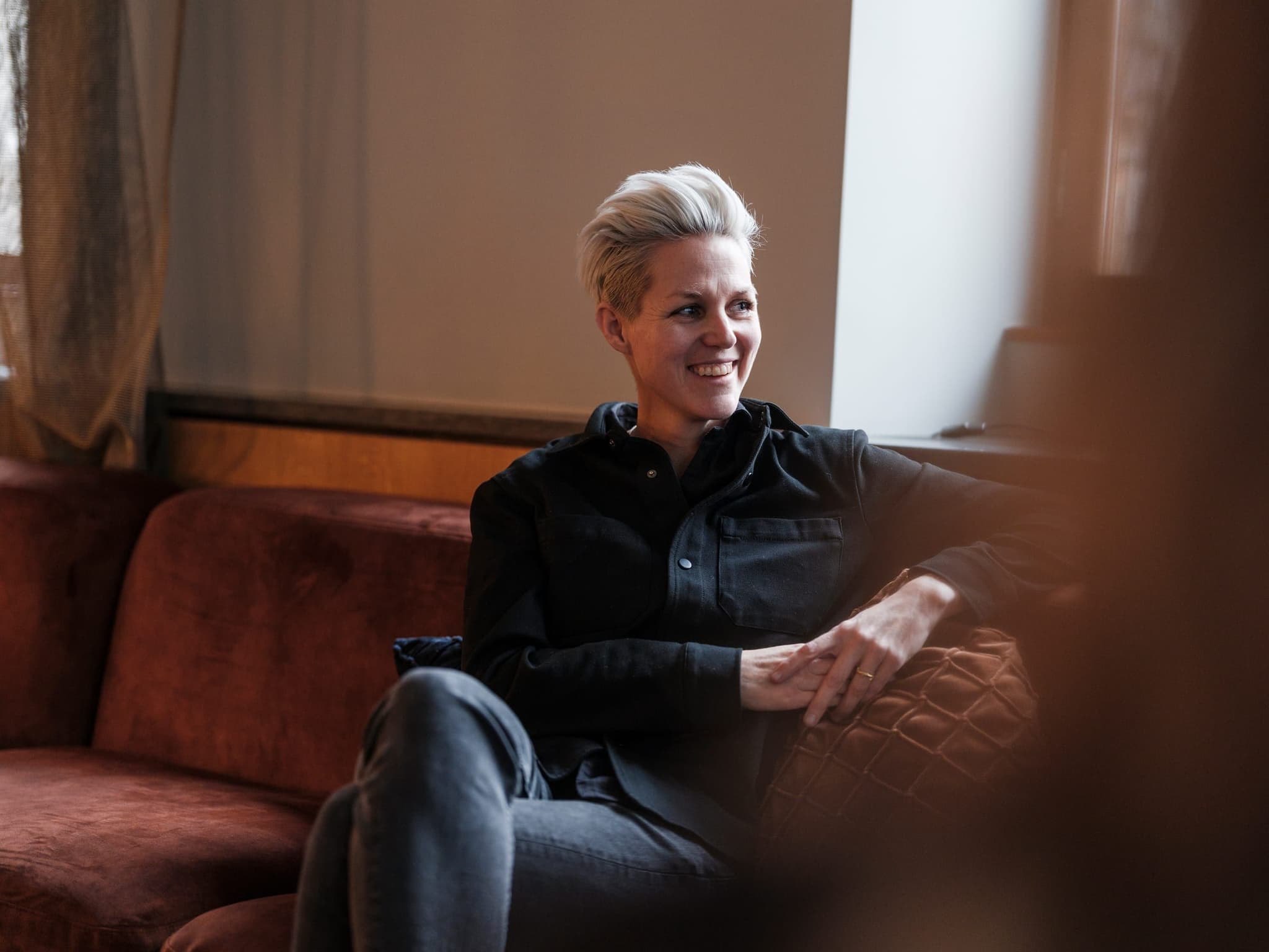 A Curamando consultant sitting on a sofa, smiling at someone off camera