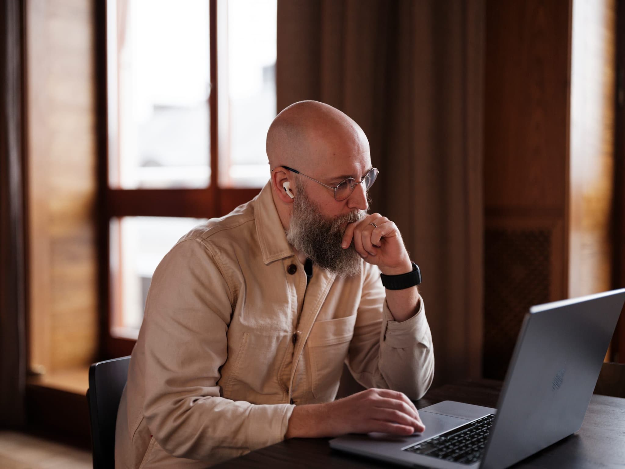 A Curamando consultant at a laptop, chin in hand, thinking