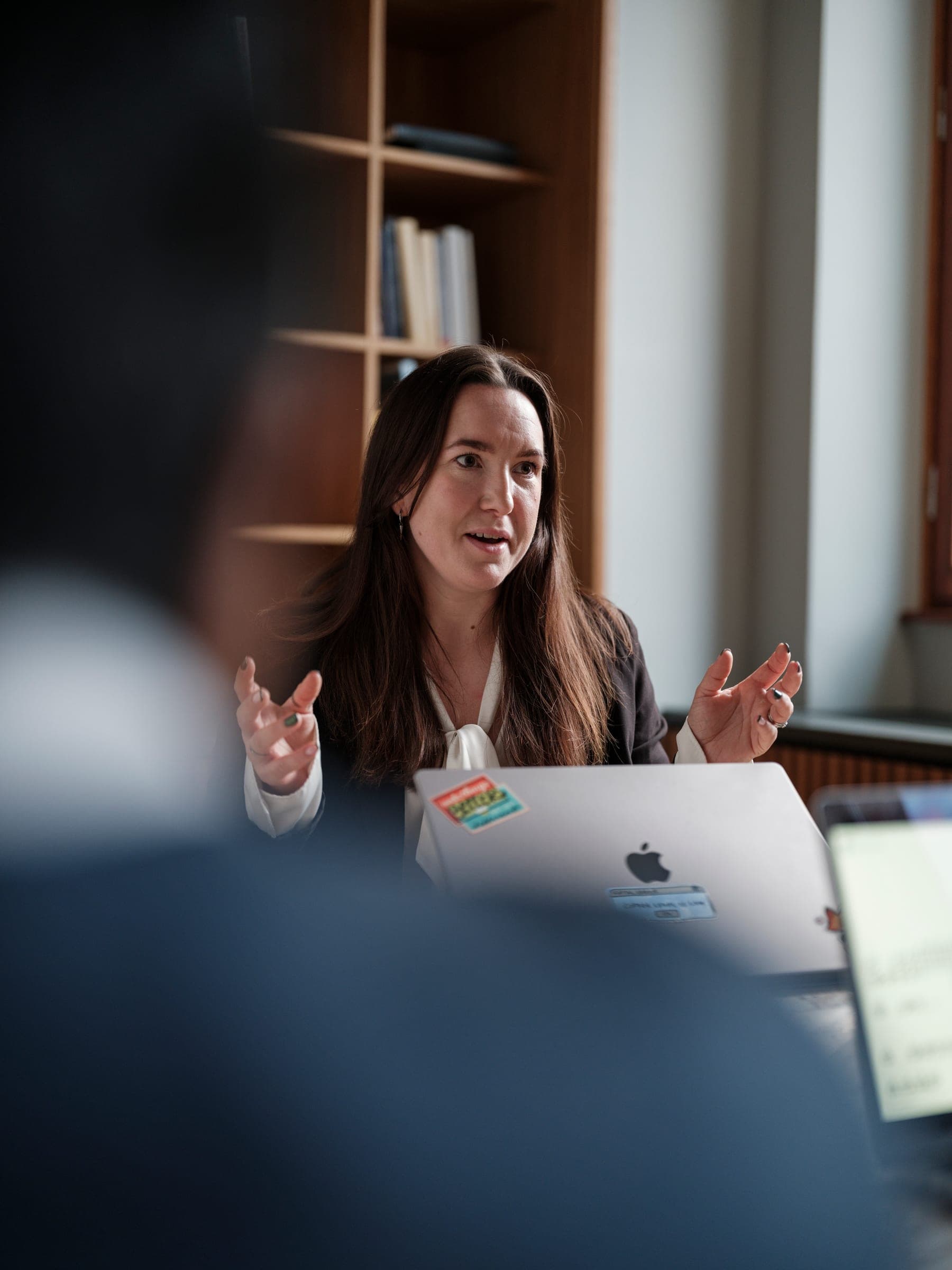 A Curamando consultant talking at a meeting table, laptop open in front of her