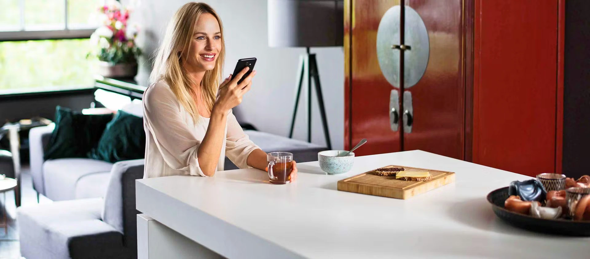 Blond, smiling woman looking at her phone, receiving delivery information from PostNL.